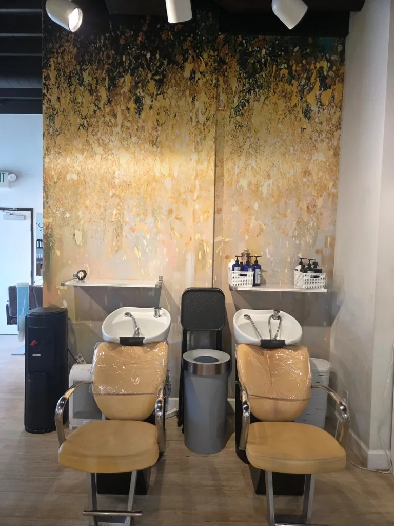 Two shampoo bowls against a gold feature wall at Glow Salon & Spa